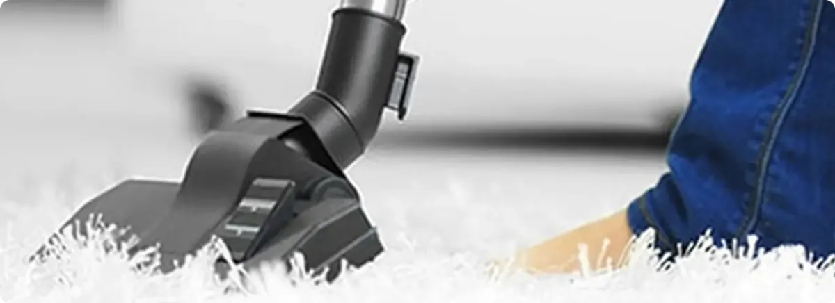 Close-up of a professional vacuuming a white carpet in Northampton.
